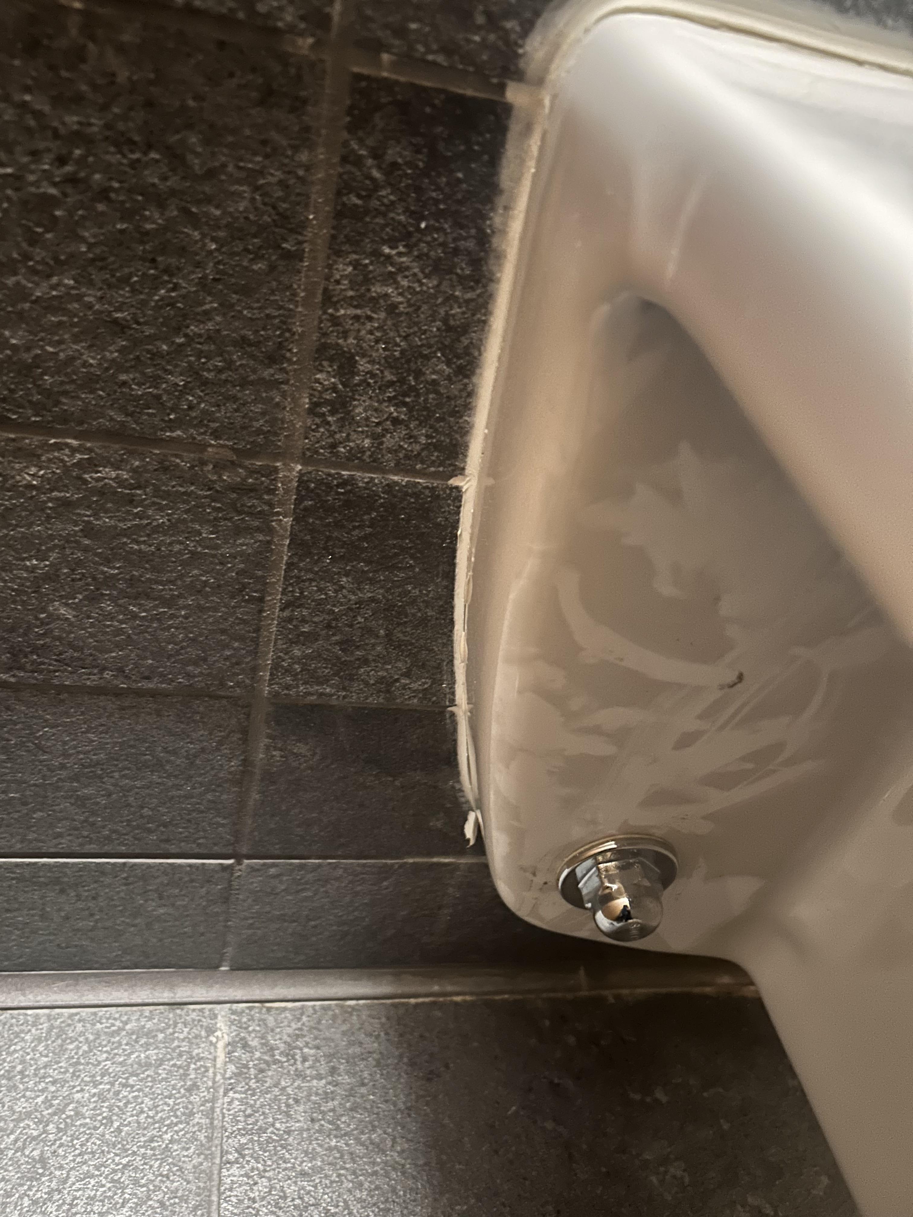 Area beneath a commercial restroom fixture before detail cleaning