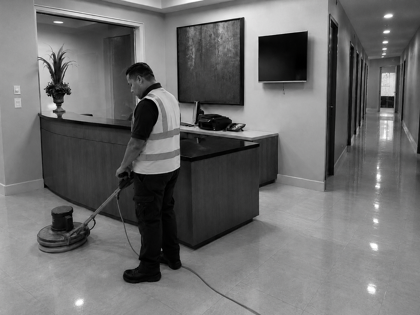 Facility care professional buffing a polished floor in a commercial reception area